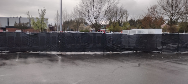 screened fence surrounding a tesla charging station obscuring the damage to the equipment