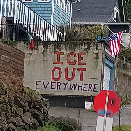 10' concrete retaining wall of a house in NW Seattle with 'ICE OUT Everywhere' painted full height